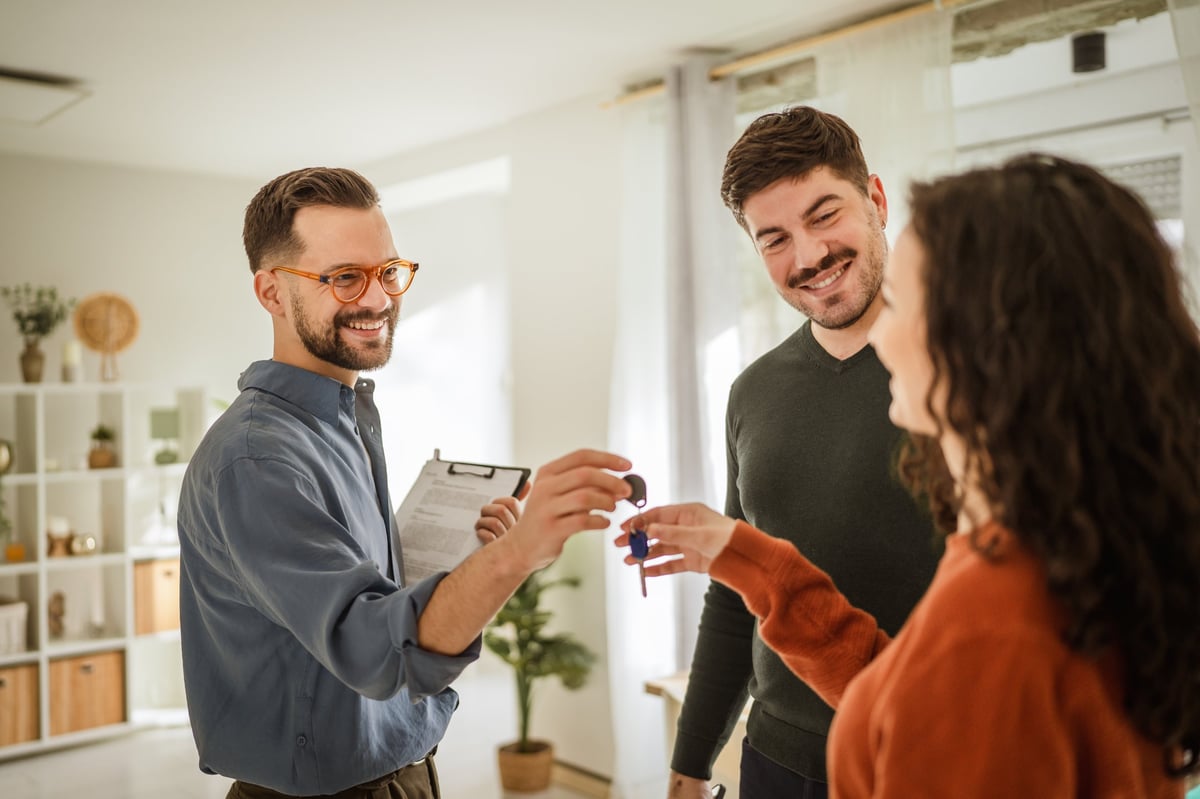 Property manager handing the keys of a newly leased apartment to happy tenants